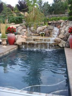 a pool with a waterfall and two large vases filled with flowers on the side