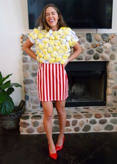 a woman standing in front of a fire place with flowers on her shirt and red high heels