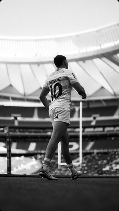 black and white photograph of a soccer player in the middle of a field with his hands on his hips