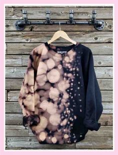 a black and pink sweatshirt hanging on a wooden wall