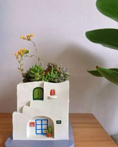 a small house planter with succulents in it