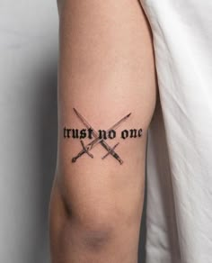 two crossed swords with the words trust no one tattooed on their arm and behind them