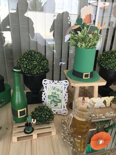 a table topped with lots of potted plants next to a green bottle and glass