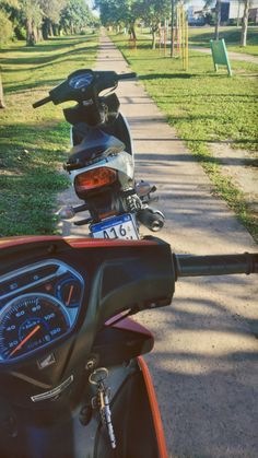 a row of motorcycles parked on the side of a road next to a grassy field