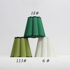 four different colored lamps sitting next to each other on top of a white tablecloth