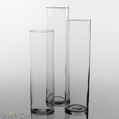 three tall glass vases sitting next to each other on a white surface with no one in it