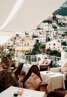 an outdoor dining area with tables and chairs on the balcony overlooking a cityscape