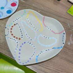 two plates with different designs on them sitting on a wooden table next to paintbrushes