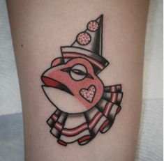 a woman's leg with a red and black clown face tattoo on the thigh