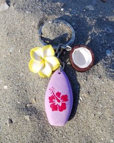 Hawaiian style summer fashion. Surfboard shaped keychain or beach bag charm, adorned with two yellow and white plumeria flower charms and a half coconut. The surfboard is made from lavender colored clay and decorated with a dark pink hibiscus. Perfect gift for surf and beach lovers of all ages. APPROXIMATE MEASUREMENTS: Total length: 8 cm (around 3,15" inches) Surf: 3 x 1.8 x 0.8 cm (1,18" x 0,71" x0,31" inches) Flower: 2 x 2 x 1 cm (0,79" x 0,79" x 0,39" inches) Coconut: 1.5 x 1.5 x 0.7 cm (0,5 Hibiscus Flower Keychain, Clay Summer Ideas, Surf Board Ideas, Coconut Girl Accessories, Coconut Girl Wishlist, Summer Things To Buy, Surf Boards Aesthetic, Summer Clay Ideas, Surf Keychain