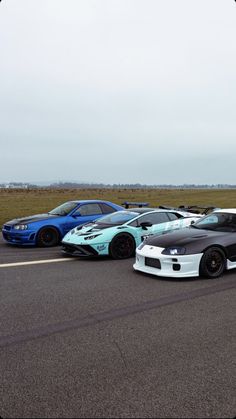 four cars are lined up in a row on the road, one is blue and one is white