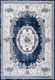 a blue and white rug with an ornate design on the center, surrounded by scrolls