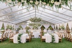 an outdoor tent with tables and chairs set up for a wedding reception in the grass