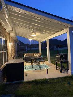 a covered patio with table and chairs at night