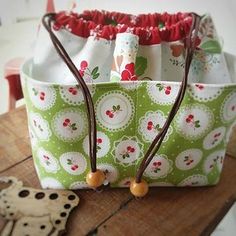 a green and white flowered bag sitting on top of a wooden table