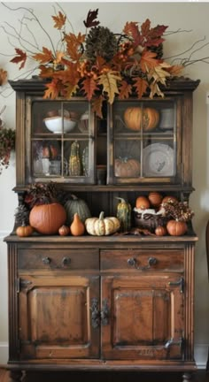 an old china cabinet decorated with fall leaves and pumpkins