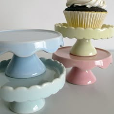 three different colored cupcakes sitting next to each other on top of cake plates