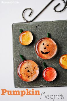 pumpkin magnets with faces on them are sitting on a slate board next to a pair of scissors