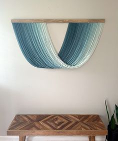 a wooden bench in front of a wall with blue drapes hanging on it's side