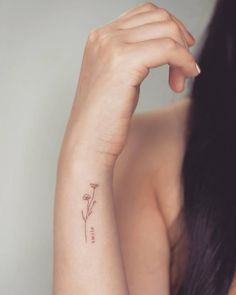 a woman's arm with a small flower tattoo on the left side of her arm