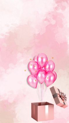 pink balloons are floating in the air over a box