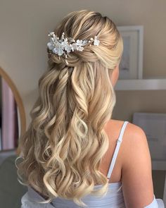 a woman with long blonde hair wearing a white flowered headpiece in her hair