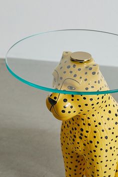 a glass table topped with a yellow and black cheetah figurine under a glass top