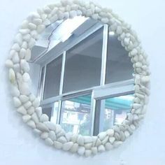 a round mirror hanging on the side of a white wall next to a windowsill