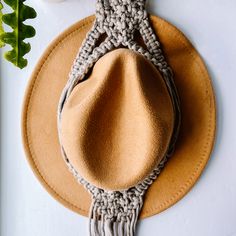 a brown hat on top of a white table next to a pot holder and plant