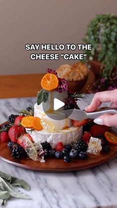 someone is cutting into a cake with fruit on it and the words say hello to the cheesecake