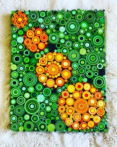 an abstract painting with circles and dots in green, orange, and yellow on a white furnishing