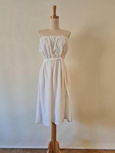 MGA Fabulous white terry towelling strapless beach dress.  In a thick luxurious terry, this simple dress has an elasticated turn down at the top edge and a simple elastic waist.  Finishing just below the knee this has two side splits and a long tie belt with bely loops on either side at the waist.  In lovely condition estimate this to be a late 80s or 90s garment based on the care label.  This is the perfect post swim or beach dress.  Marked a size 14 this is closer to a 10-12 today however there is some good stretch to this piece so refer to measurements.  White.  Acetate Nylon Towelling.  Made in Australia. Excellent Condition, this has been washed and is ready to be worn.  Body Length from top edge - 86cm   Upper edge Width relaxed - 36cm  Bust - 41cm  Waist Relaxed - 29cm  Waist Stretc Strapless Beach Dress, Terry Towelling, Tie Length, Late 80s, Simple Dress, Terry Towel, Dress With Tie, Good Stretches, Dress Clothes For Women