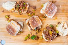 several small sandwiches with meat and vegetables on a wooden cutting board, ready to be eaten