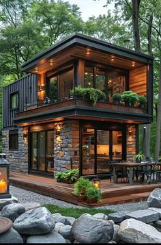 a small house with lots of windows and plants on the roof, surrounded by rocks