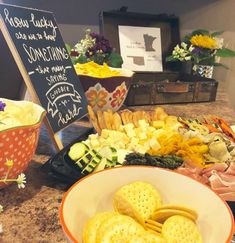 a table topped with lots of different types of crackers next to a bowl filled with flowers