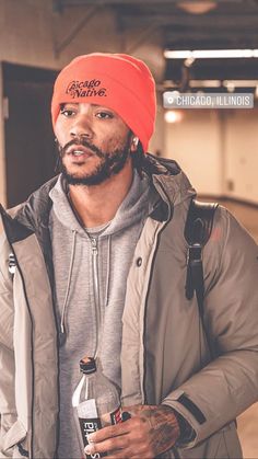 a man wearing a red beanie and holding a bottle of water in his hand