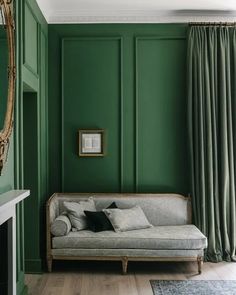 a living room with green walls and wood flooring in the corner, along with a couch