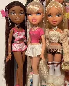 three dolls are standing next to each other in front of a wall full of stuffed animals