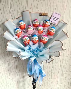 a bouquet of eggs wrapped in blue and pink ribbon on a tripod with a note attached to it