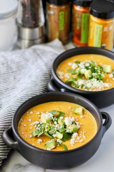 two black bowls filled with soup on top of a table