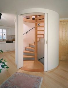 a spiral staircase in the middle of a living room with hardwood floors and white walls