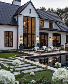 a large white house with a pool in the front yard and landscaping around it at dusk