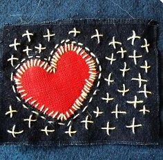 a patch with a red heart on it in the middle of some blue fabric and white crosses