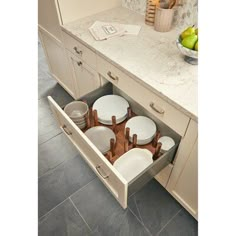 an open drawer in the middle of a kitchen with plates and utensils inside