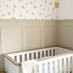 a white crib in the corner of a room with sheep wallpaper on the walls