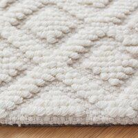 a close up view of a white rug on the floor with wood floors in the background