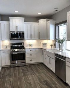 a large kitchen with white cabinets and stainless steel appliances, along with hardwood flooring