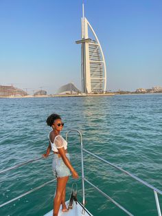 a woman standing on the edge of a boat in front of a burj