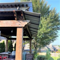 an outdoor covered patio with grills and tables in the back yard, surrounded by trees