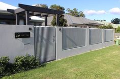 a house with a fence in front of it and some bushes on the other side